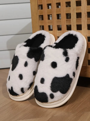 Cow print faux fur house slides with black and white pattern and plush lining.