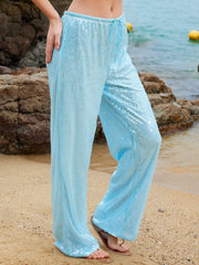 Light blue sequin wide-leg pants with drawstring waist, styled on a beach.