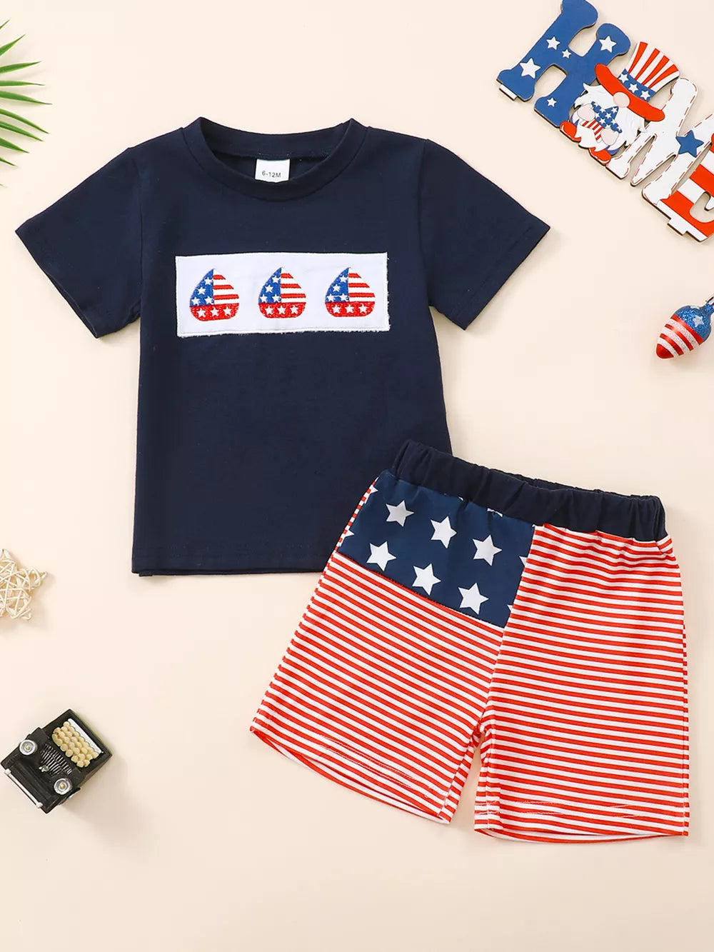 Navy American flag baby set with three flag patches on shirt and striped shorts.