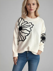 Cream knit sweater with black floral applique detail on chest and sleeve.