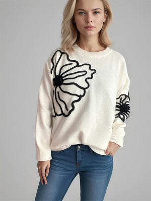 Cream knit sweater with black floral applique detail on chest and sleeve.