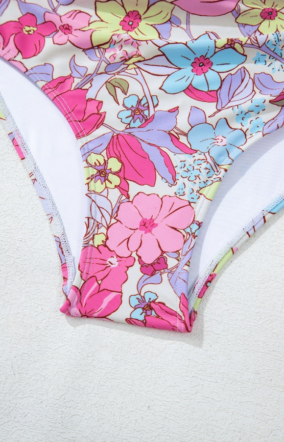 Floral one-piece swimsuit in fuchsia pink with a backless design and ruffle detail.