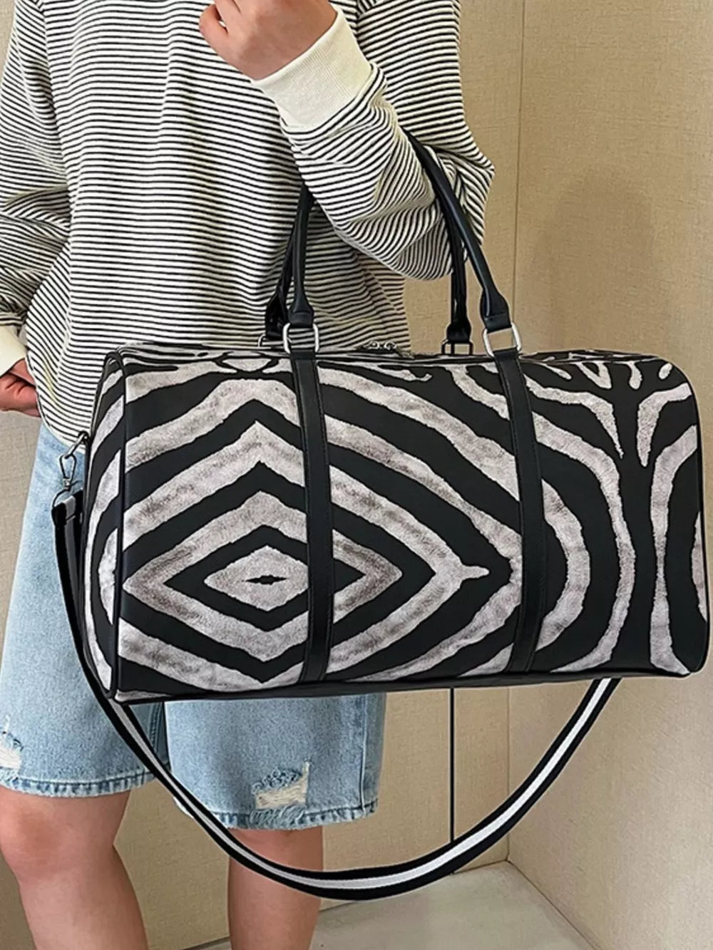 Large black and white zebra print duffle bag with carry handles and detachable strap.