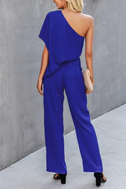Royal blue asymmetric drape-sleeve wide-leg jumpsuit with a cinched waist.