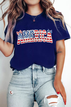 Patriotic graphic t-shirt with AMERICA text in red, white, and blue flag pattern and bow details.