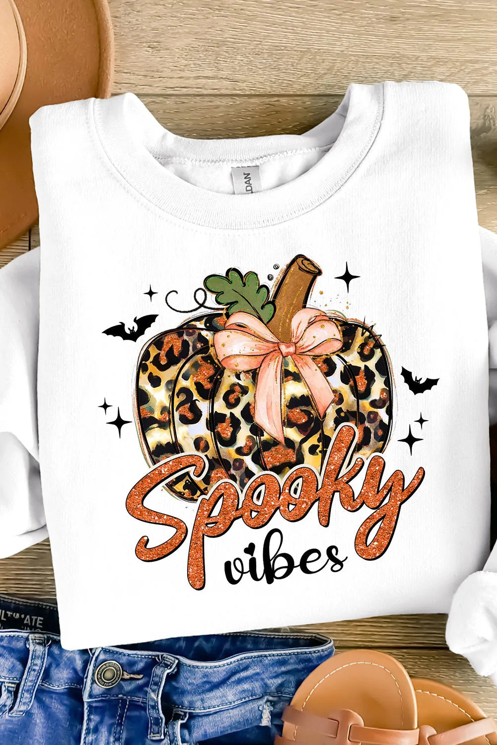 White crewneck sweatshirt with a leopard print pumpkin graphic and "Spooky vibes" text.
