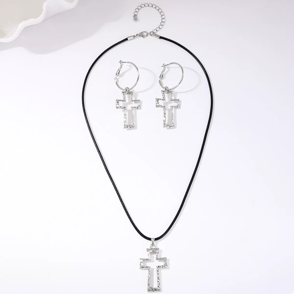 Silver cross pendant necklace and hoop earrings set with black cord chain.