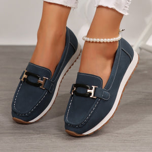 Dark blue slip-on loafers with buckle detail and contrast stitching.