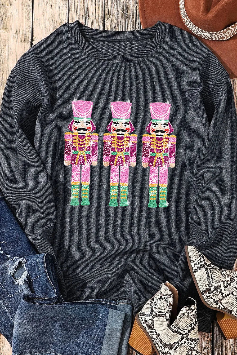 Black ribbed sweatshirt with three pink nutcracker embellishments.