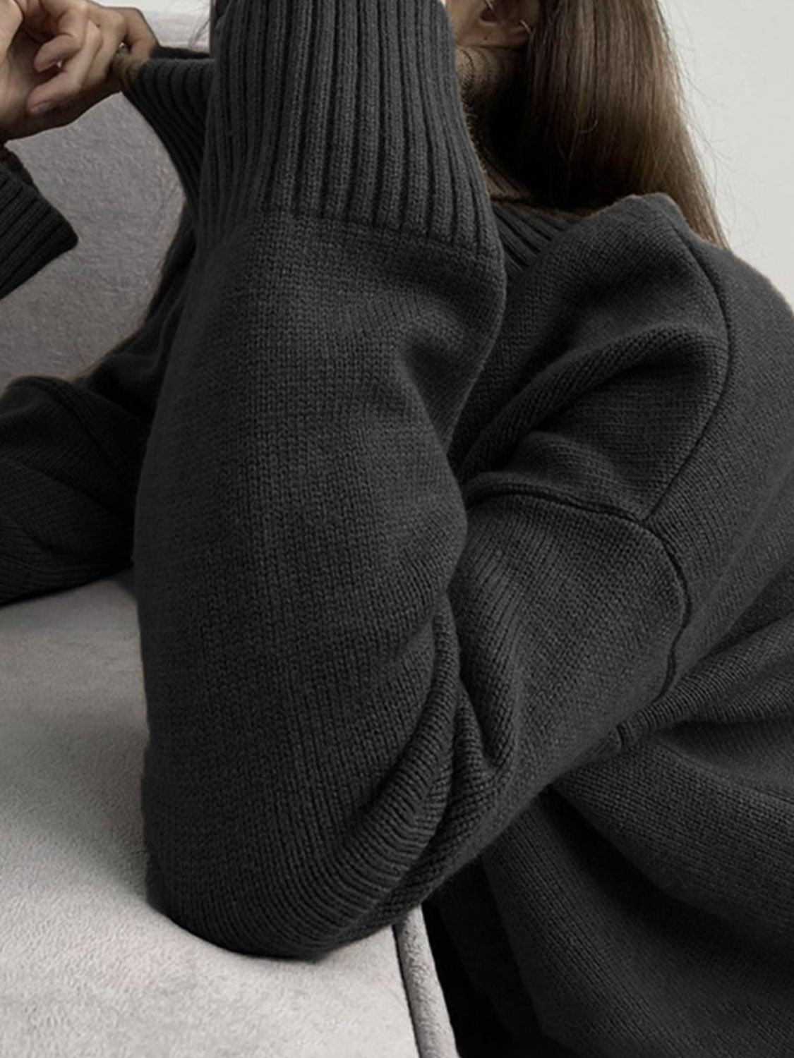Black ribbed turtleneck sweater with flared sleeves and textured knit detail