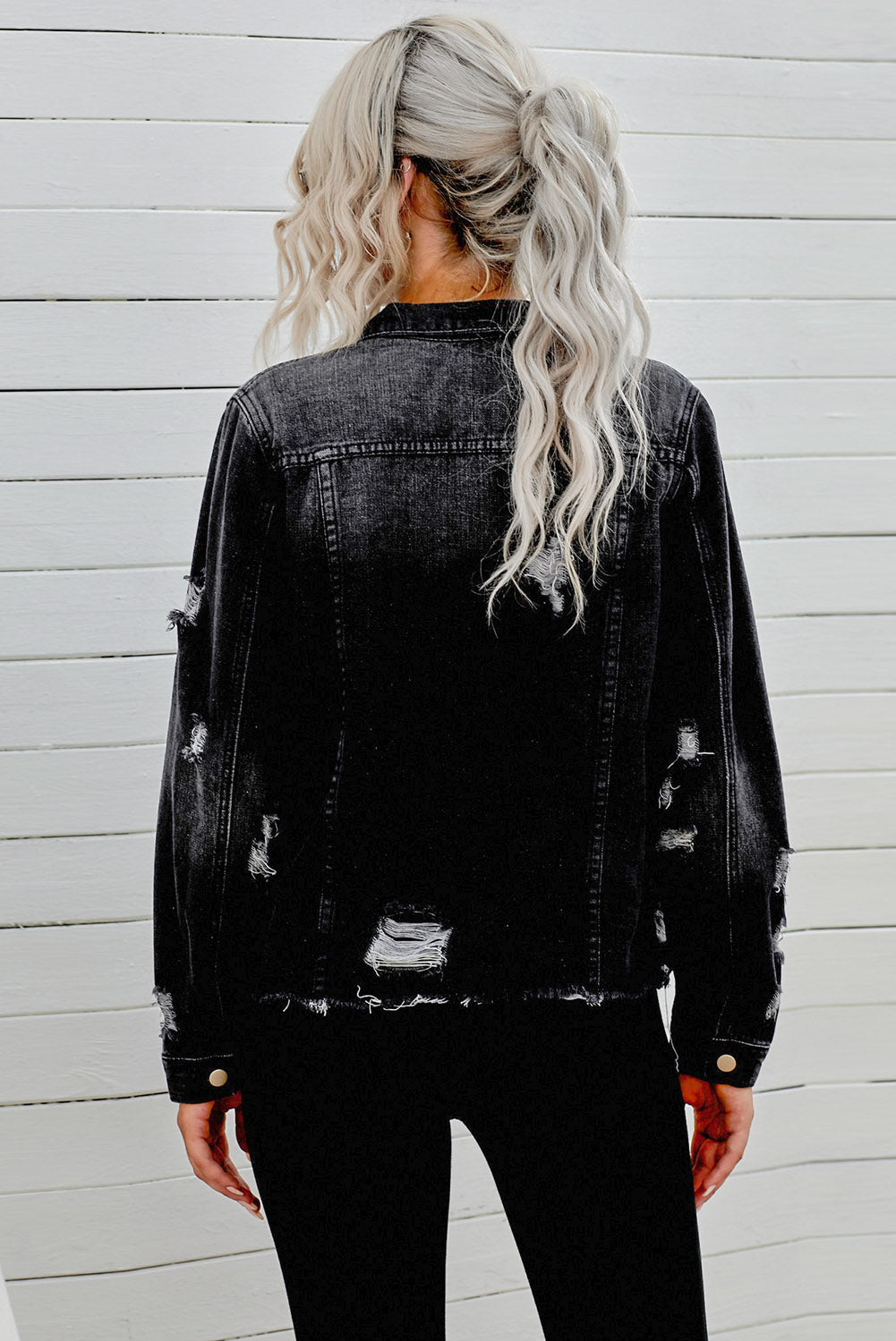 Black distressed denim trucker jacket with frayed edges and ripped details.