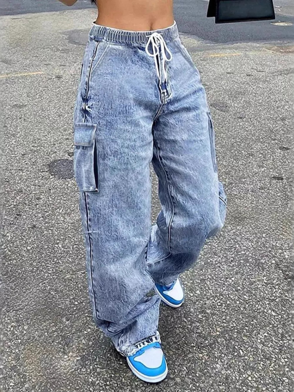 Relaxed high-waisted light wash denim cargo pants with drawstring and side pockets.