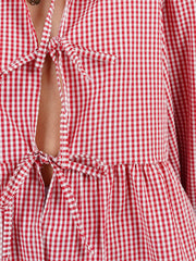 Red gingham tie-front peplum blouse with voluminous sleeves and a tie closure.