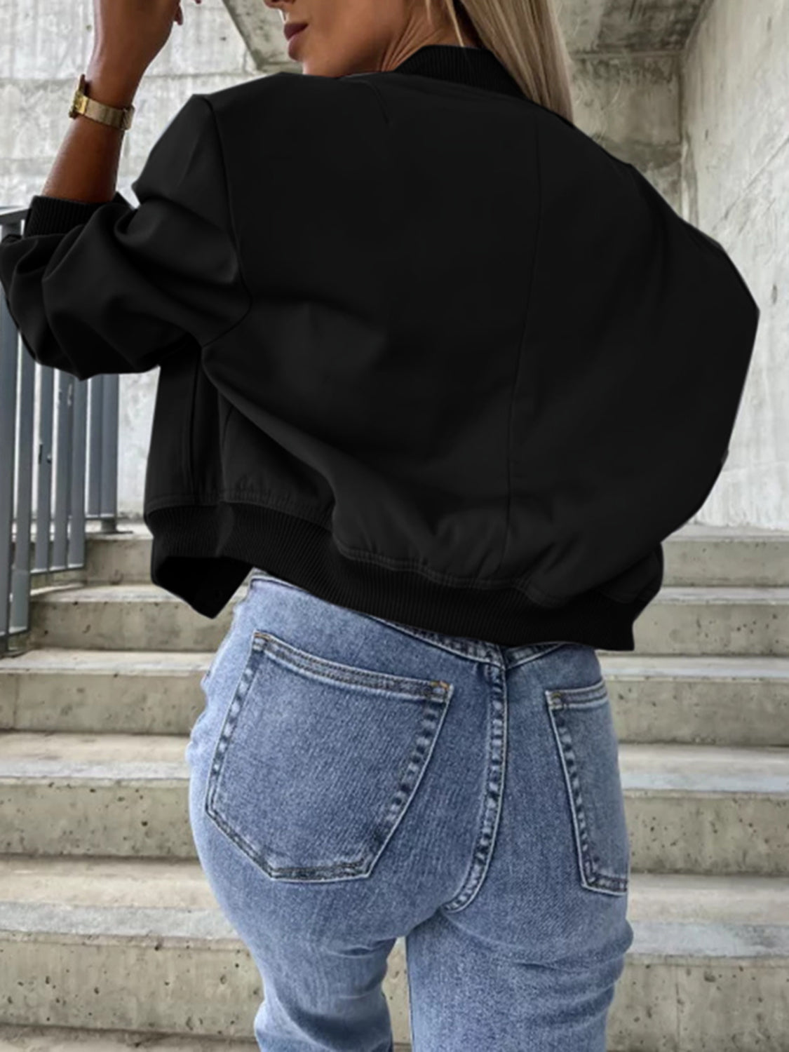 Black faux leather bomber jacket with sculpted sleeves and ribbed cuffs.