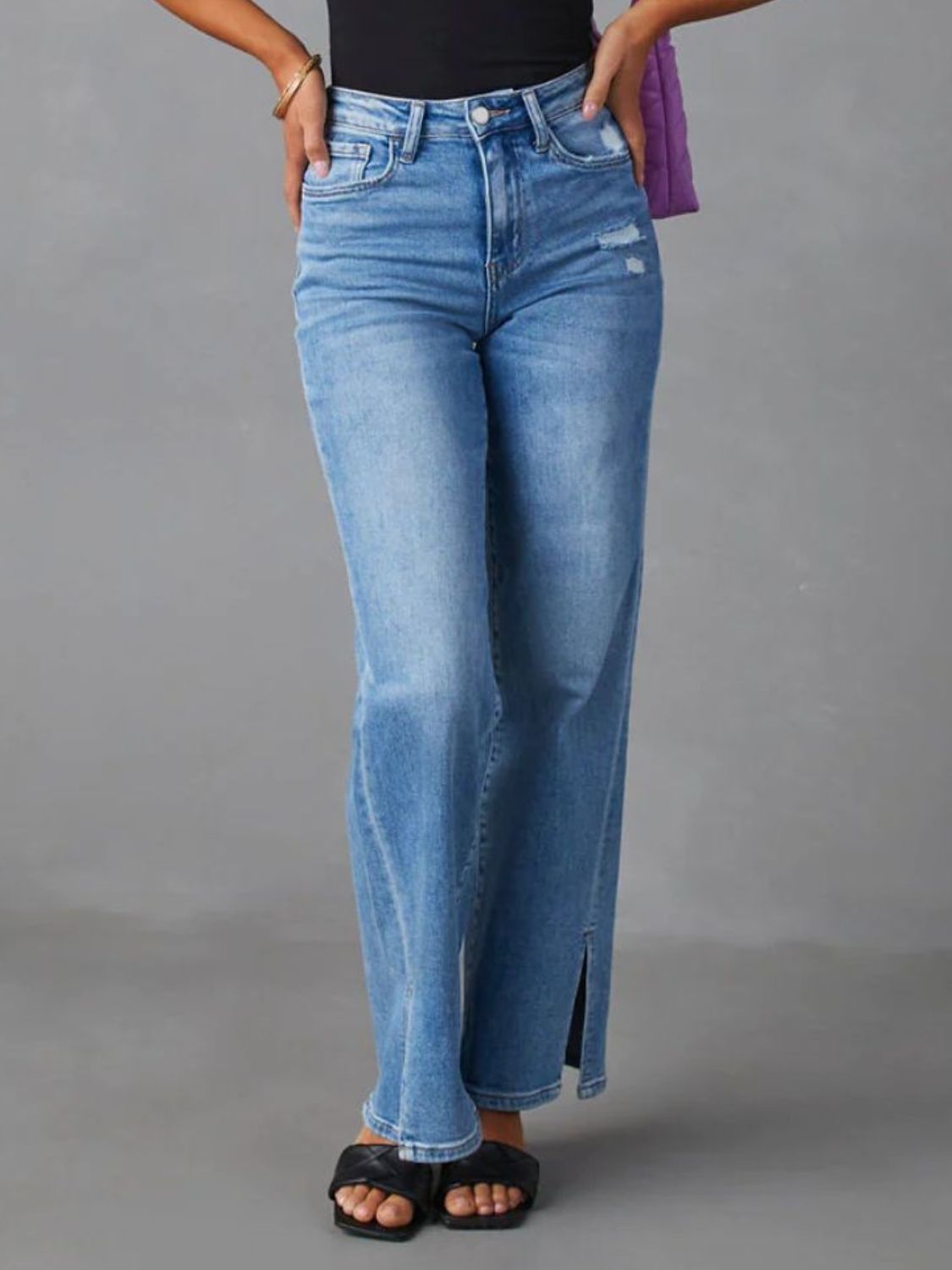 Medium wash split hem flare jeans with distressed details and a button closure.