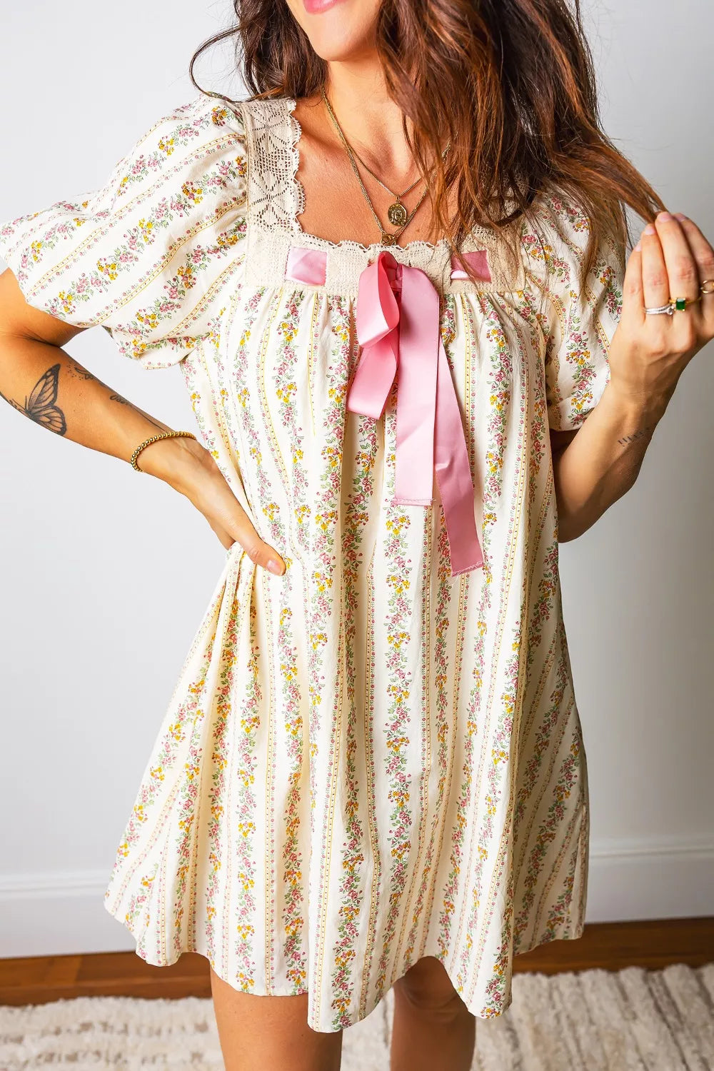 Floral lace-trim mini dress with puff sleeves, square neckline, and pink bow detail.