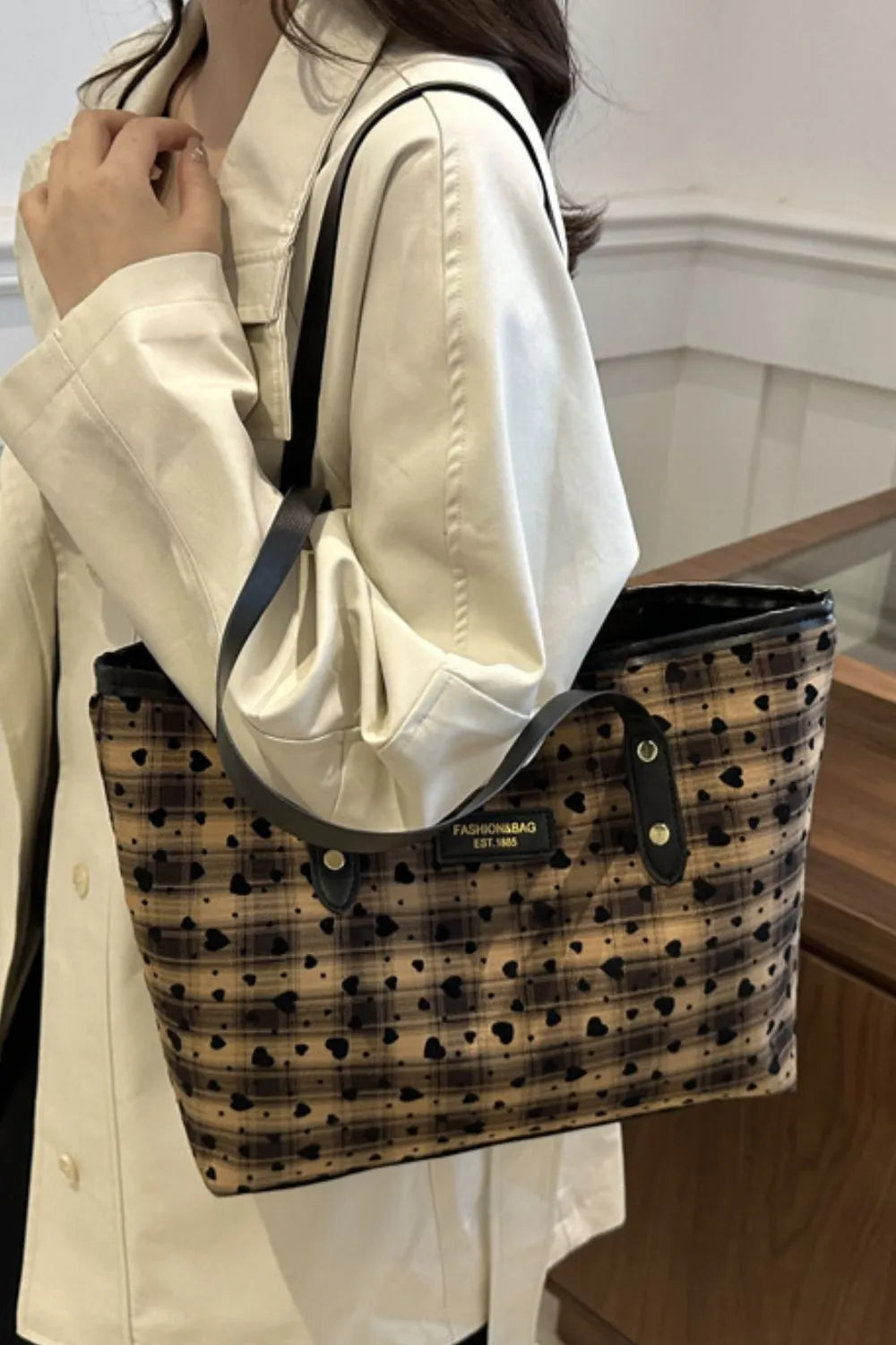 Camel plaid tote bag with black heart pattern and leather trim.