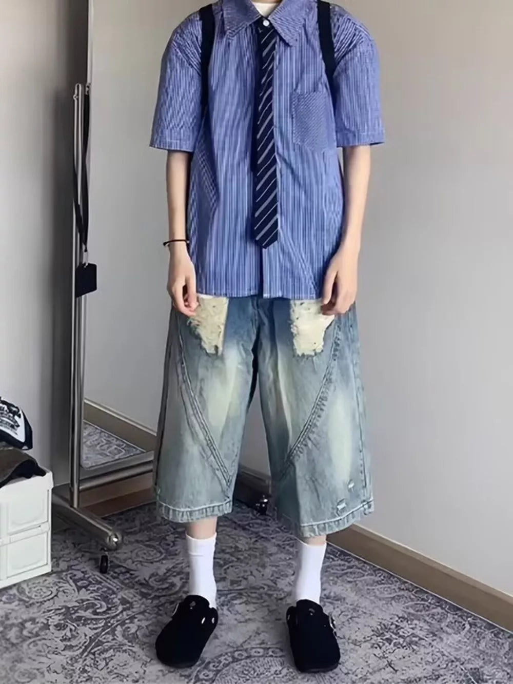 Men's relaxed fit distressed denim shorts in light wash with ripped details and wide leg.