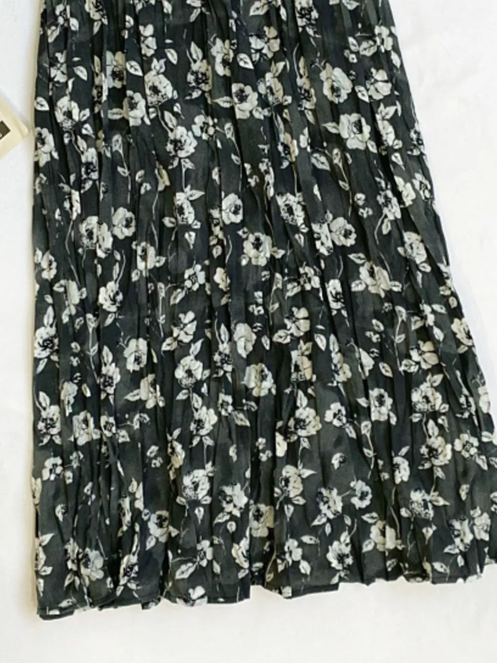 Botanical pleated midi skirt in black with a white floral print and crinkled texture.