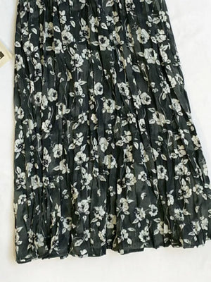 Botanical pleated midi skirt in black with a white floral print and crinkled texture.