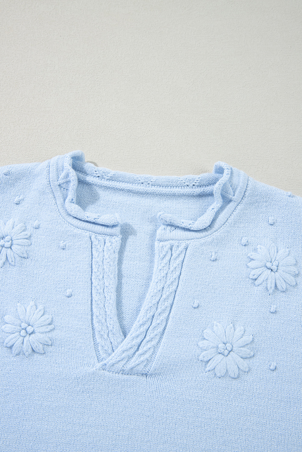 Sky blue knit sweater with embroidered floral details and notch neck.