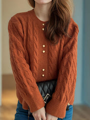 Orange cable knit cardigan with puff sleeves and gold buttons.