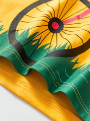 Yellow cotton t-shirt with bicycle wheel graphic and green grass detail.