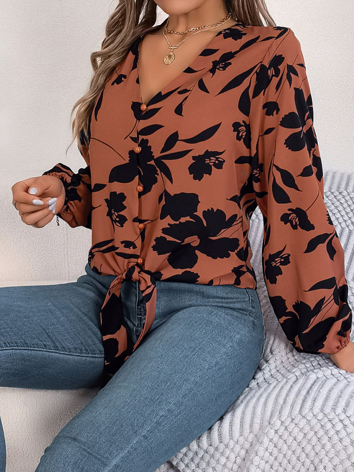 Brown floral knot-front blouse with button detail and ruffled cuffs.