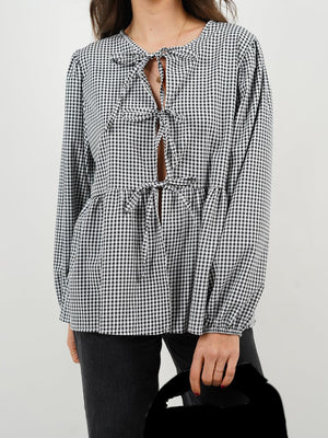 Black and white gingham tie-front peplum blouse with voluminous sleeves and a keyhole neckline.