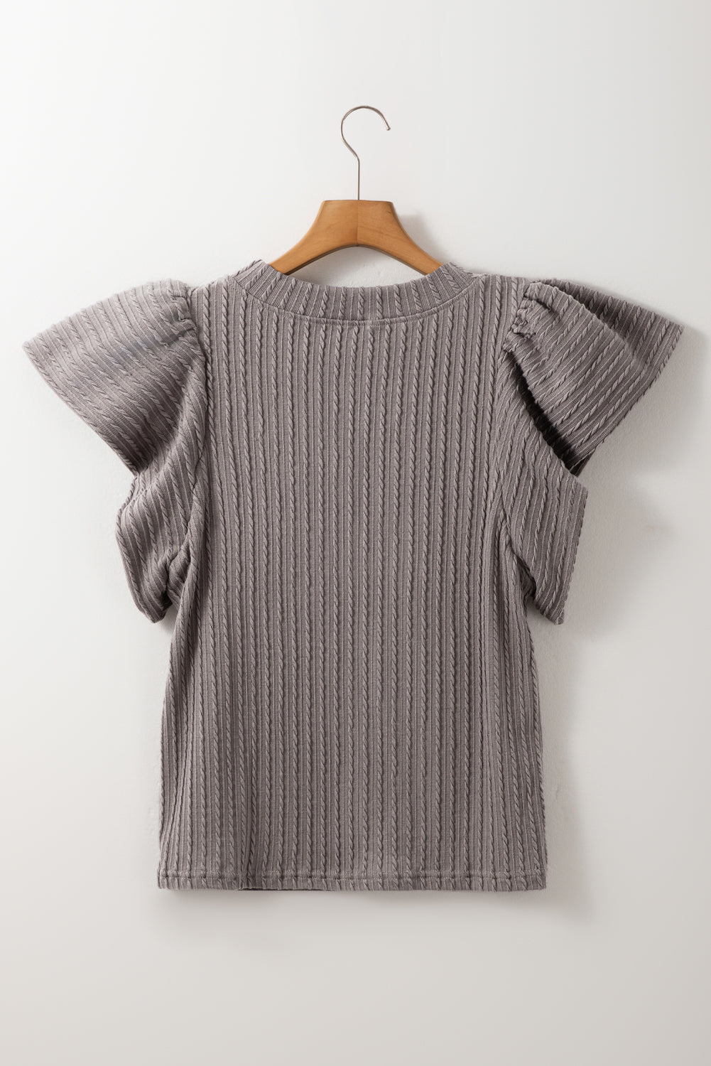 Gray cable knit top with textured fabric and flutter sleeves.