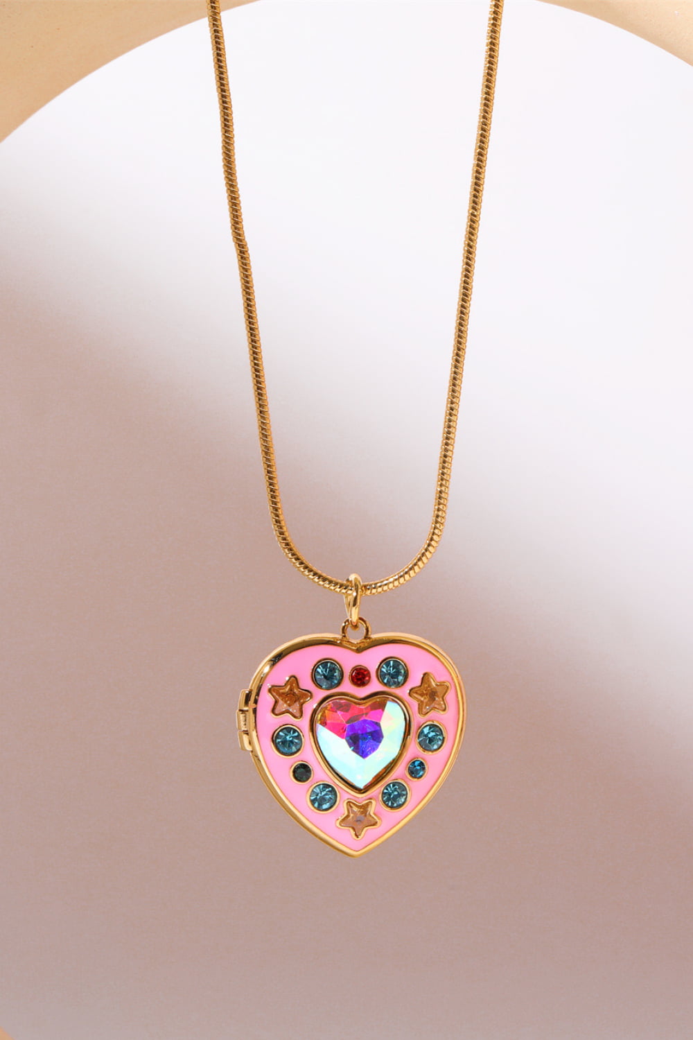 Gold locket heart pendant necklace with pink enamel, iridescent gem, stars, and blue gems