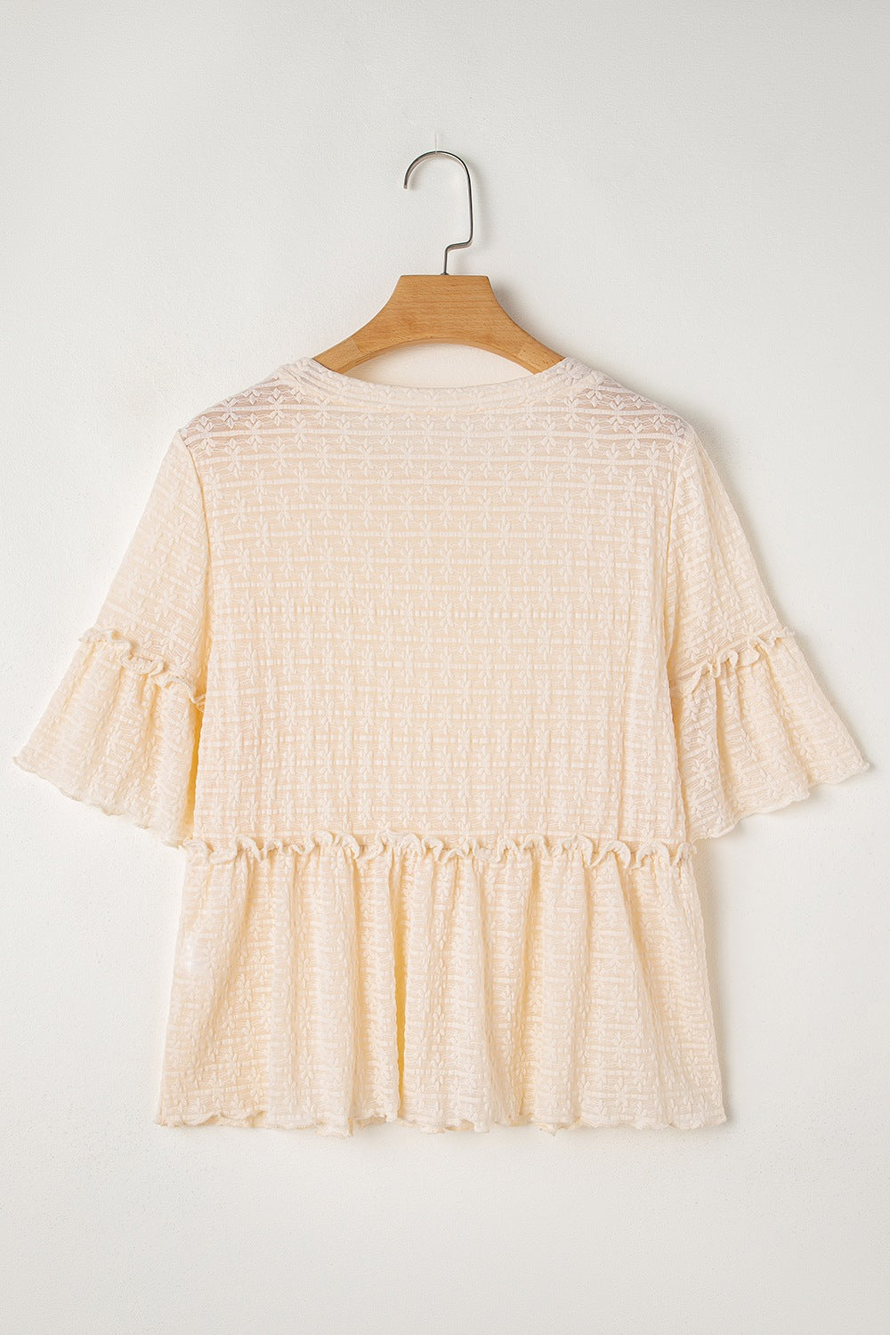 Beige textured blouse with ruffle hemline and flutter sleeves.