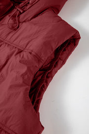 Burgundy quilted puffer vest with hood and adjustable drawcord detail.