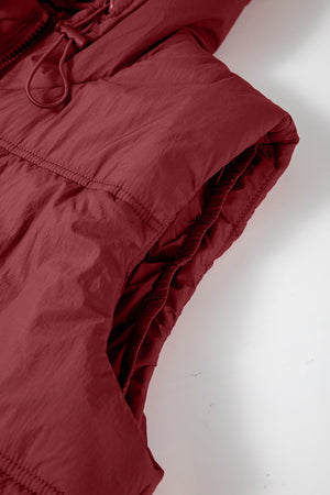Burgundy quilted puffer vest with hood and adjustable drawcord detail.