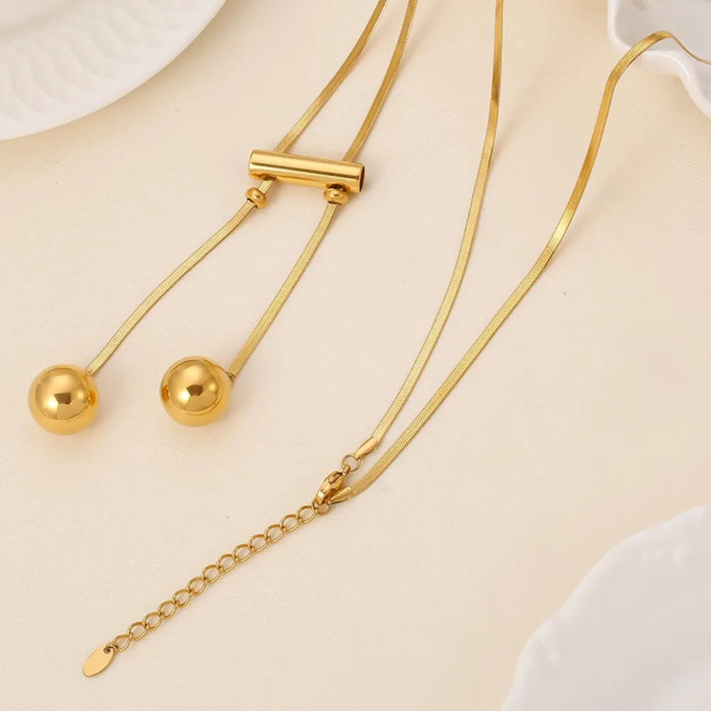 Gold lariat necklace with sphere drops and adjustable chain, 18K gold-plated.
