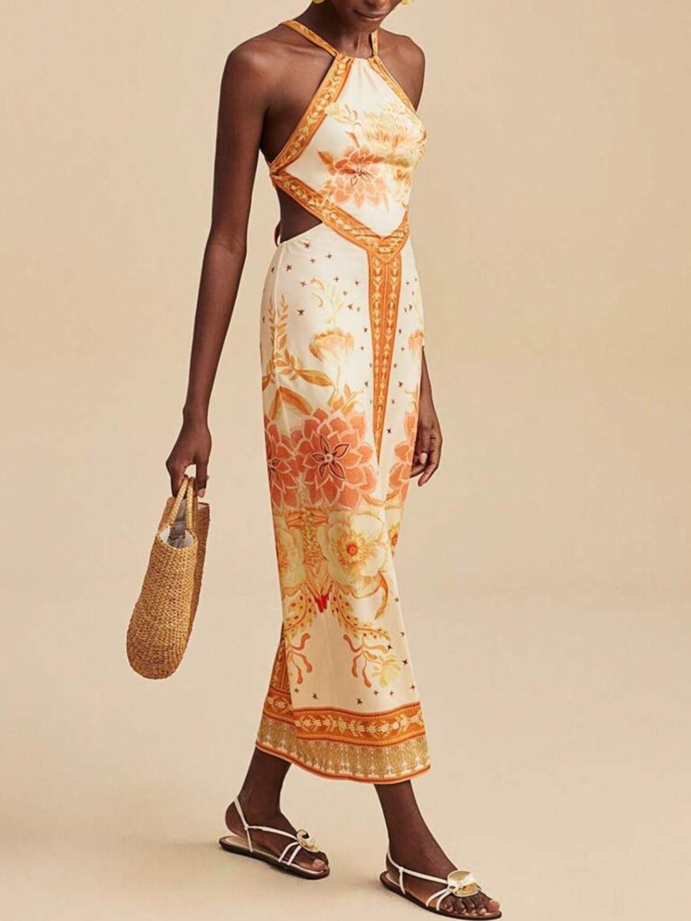 Backless maxi dress with orange floral print, halter neck, and side cutouts.