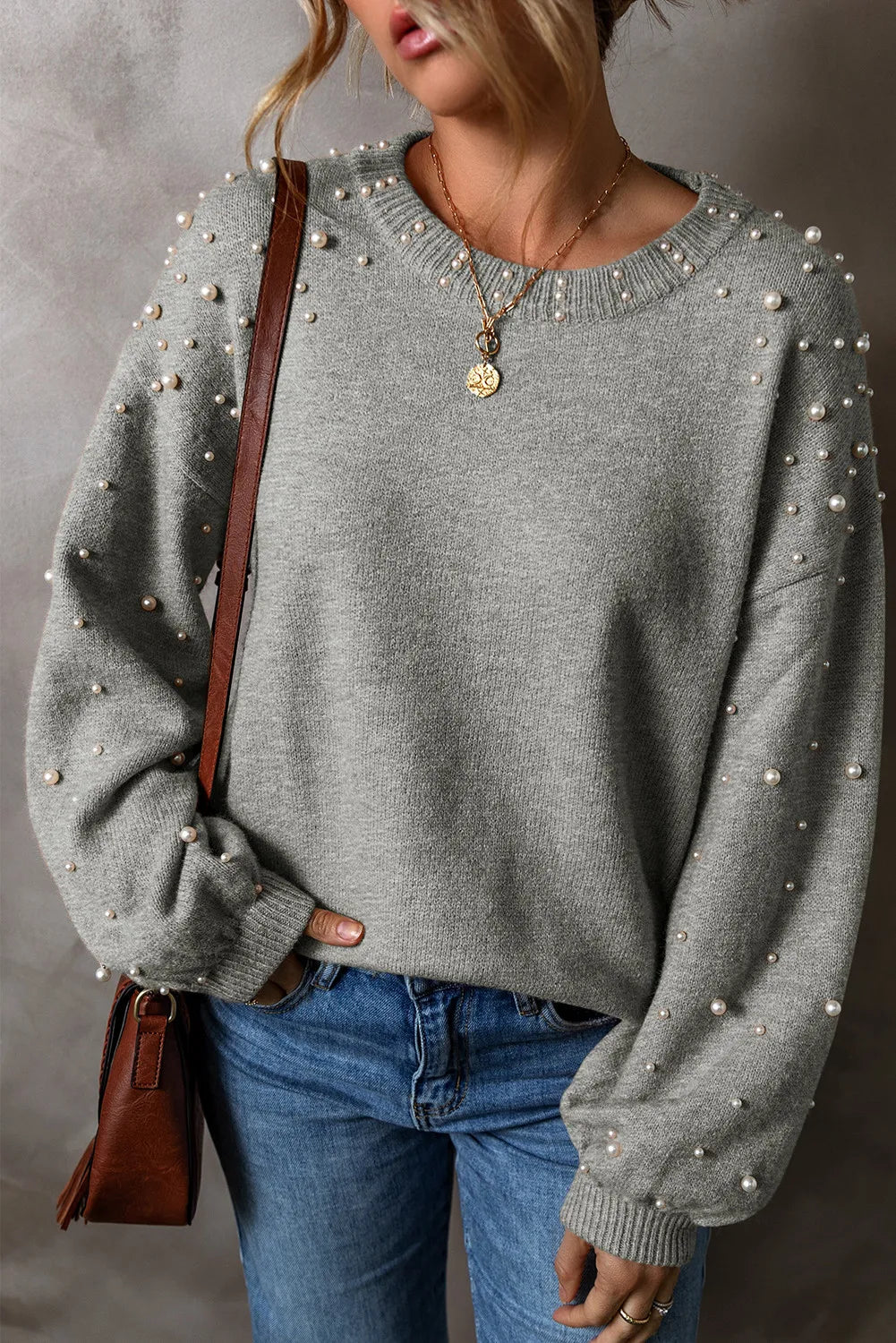 Gray knit sweater with pearl embellishments on the sleeves and neckline.