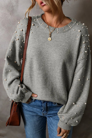 Gray knit sweater with pearl embellishments on the sleeves and neckline.