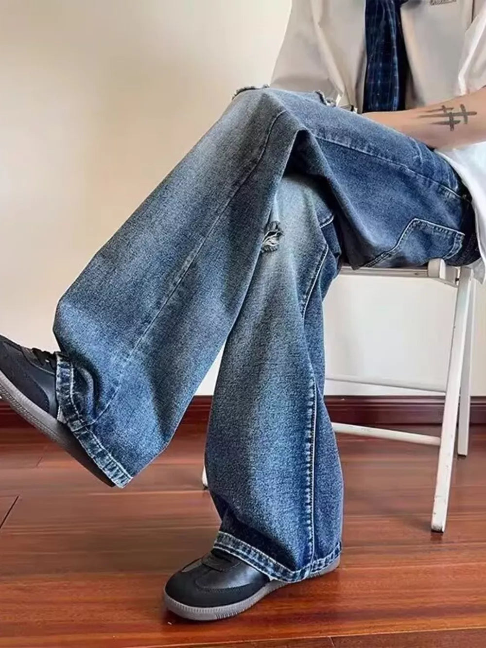 Men's distressed wide-leg jeans in blue denim with pockets and ankle pooling.