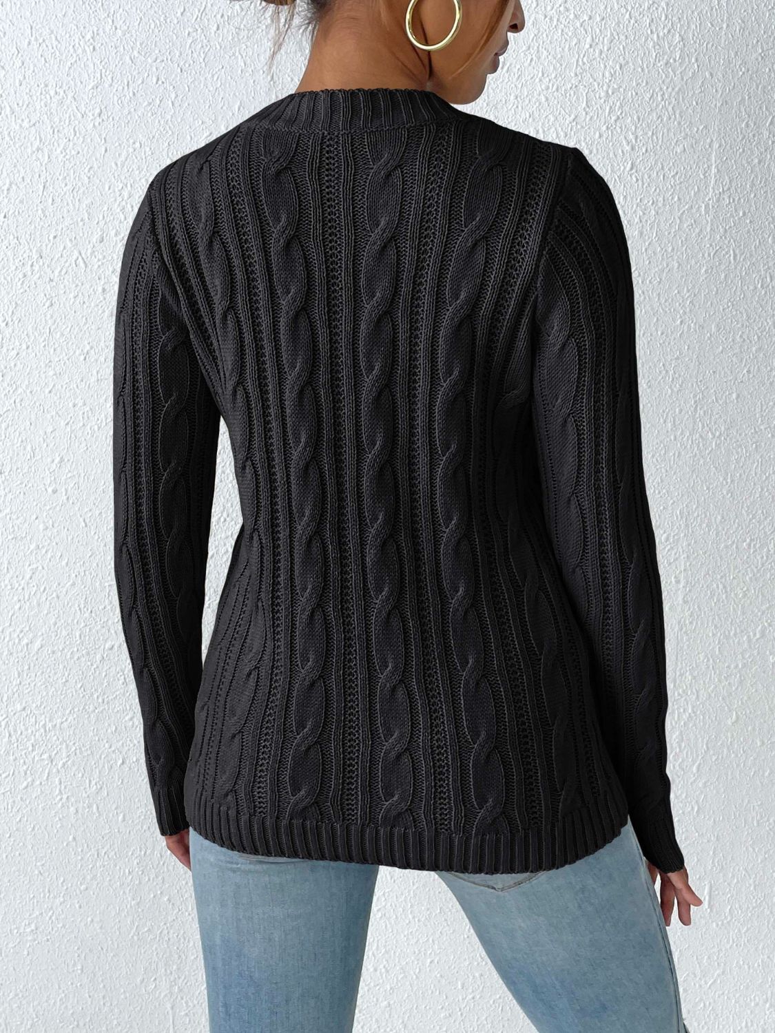 Black cable knit sweater with crew neck and long sleeves.