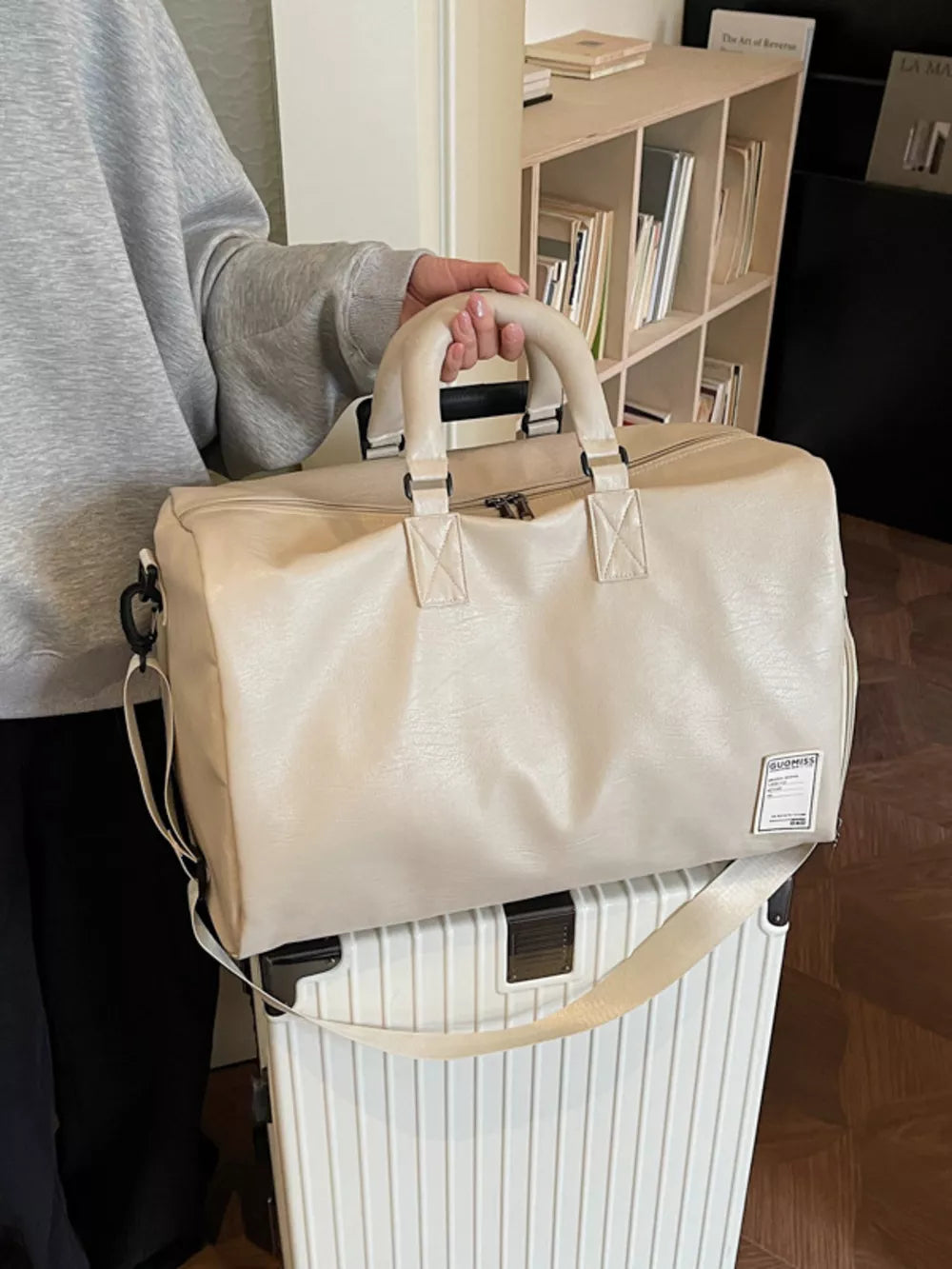 Off-white pu leather duffel bag with top handles and shoulder strap, spacious travel tote.