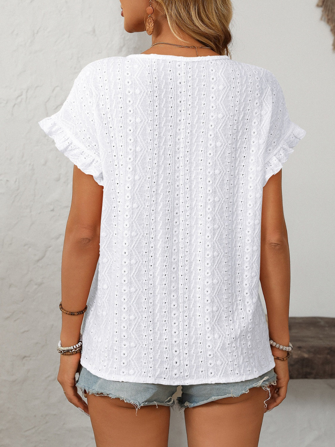 White eyelet knit blouse with ruffled short sleeves and a textured pattern.