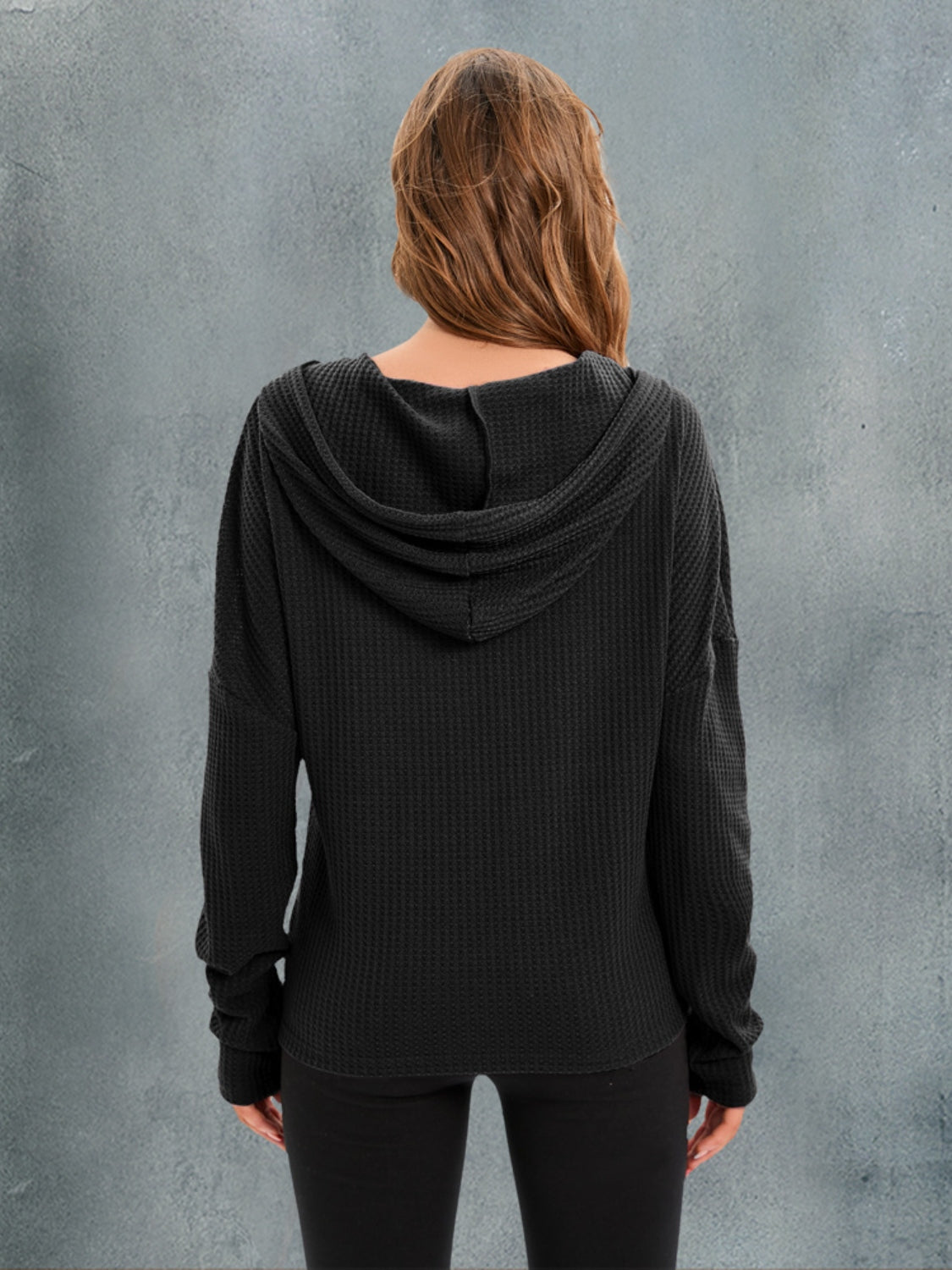 Black waffle knit relaxed fit hoodie with a hood and long sleeves.