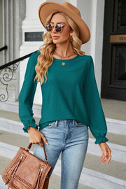 Textured puff sleeve blouse in deep teal with ruffle cuffs and a round neckline.