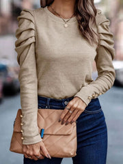 Beige knit top with ruched sleeves and gold button cuffs.