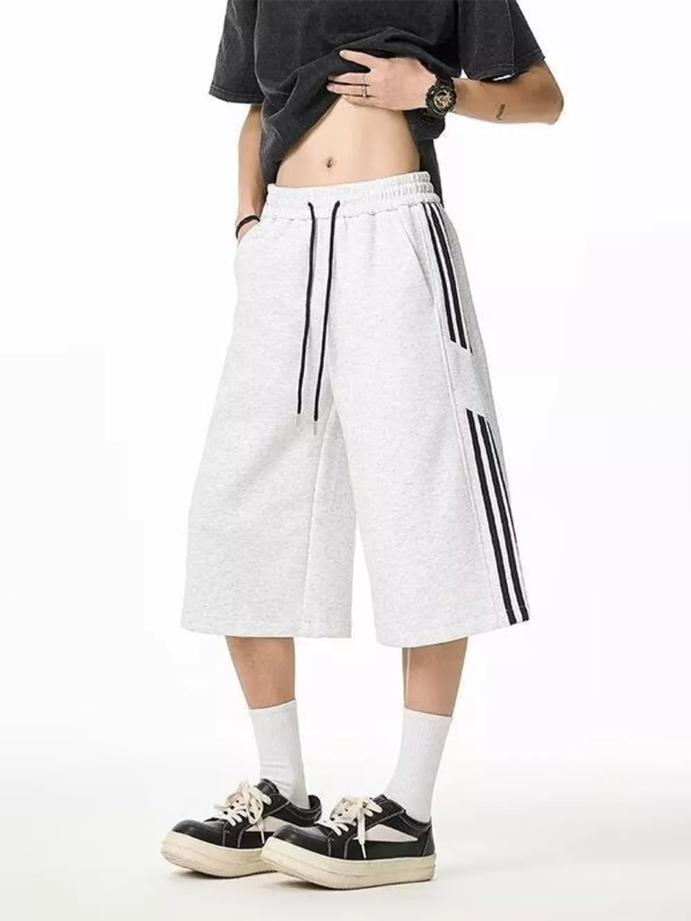 Grey sweatpants with drawstring and black side stripes, cropped length.
