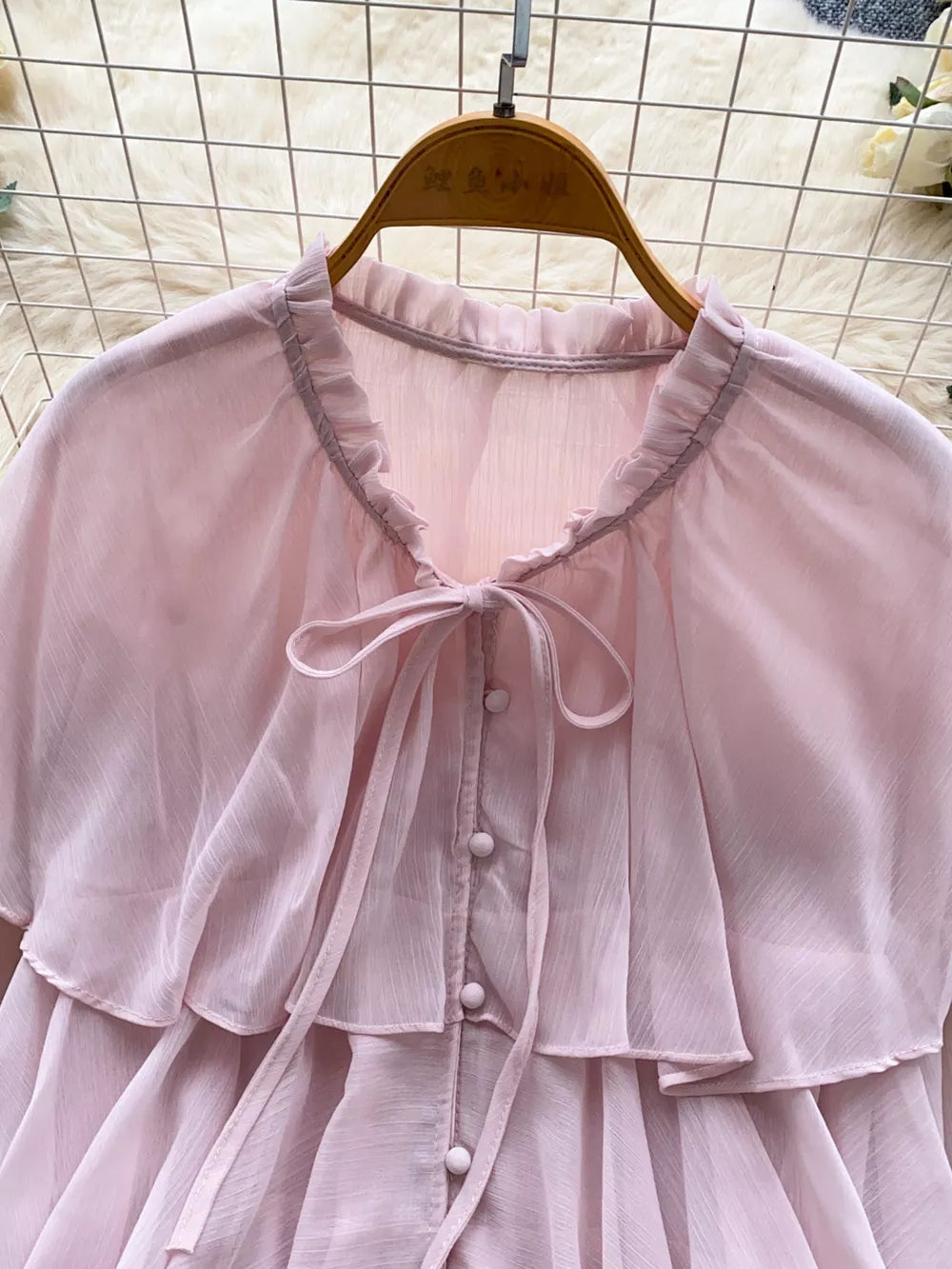 Pink chiffon blouse with ruffled neckline, bow tie, and button front.