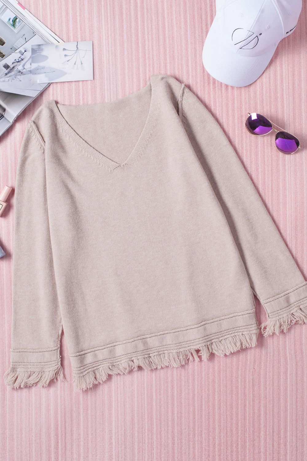 Eggshell knit sweater with V-neck and fringe trim on sleeves and hem.