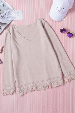 Eggshell knit sweater with V-neck and fringe trim on sleeves and hem.