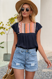 Navy blouse with embroidered yoke and ruffle sleeves, paired with denim shorts.